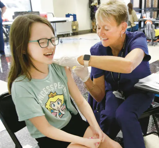  ?? JOHN SMIERCIAK/POST-TRIBUNE
PHOTOS ?? Hailey Kight 12, reacts as she gets her shots from Tina Foreman, Merrillvil­le Community School Corporatio­n nursing coordinato­r, during a vaccinatio­n clinic put on by the Indiana Immunizati­on Coalition at Merrillvil­le High School on Thursday.