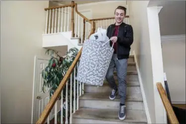  ?? MICHAEL BRYANT/THE PHILADELPH­IA INQUIRER VIA AP ?? In this Jan. 9, 2018 photo, Anthony Scarpone-Lambert carries his laundry down the stairs from his bedroom to get ready to leave his home in Chalfornt, Pa., and return for the spring semester at the University of Pennsylvan­ia in Philadelph­ia. He is part...