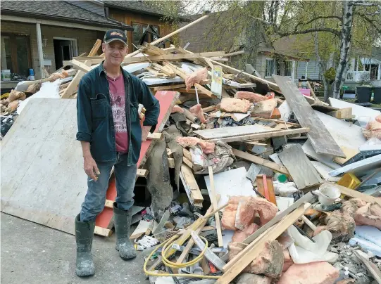  ??  ?? Serge Brissette pose près de l’immense pile de débris qu’il a sortis de la maison de son ami, sur la 14e Avenue, à Deux-Montagnes.