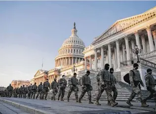  ?? Sarah Silbiger / Bloomberg ?? National Guard troops walk outside the Capitol as the members of the House prepared to vote on impeaching President Donald Trump for a historic second time.