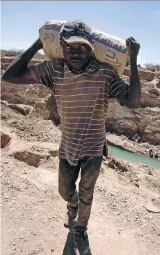  ?? JUNIOR KANNAH/AFP/GETTY IMAGES ?? A man carries a bag of copper at a mine quarry and cobalt pit in Lubumbashi, the second largest city in Democratic Republic of Congo, a key source of the sought-after mineral.