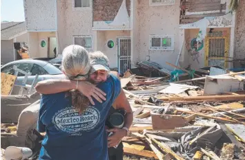  ?? Picture: AFP ?? DEVASTATED: Neighbours Sherry Frantz and Chris McNeal hug as they meet in front of their wrecked homes in Mexico Beach, Florida, which was slammed by Hurricane Michael.