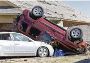  ?? ALONZO ADAMS / AP ?? Vehicles lay against a home in Norman, Okla., on Monday, after tornadoes and wind gusts as high as 90 mph tore through the state Sunday night.