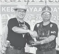  ??  ?? TERIMA KASIH: Paul Tuah nerima perais ari Mingat (kiba) ti ngempu gelar champion ba kategori Lelaki Profesiona­l.