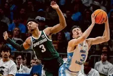  ?? ?? Mike Stewart/Associated Press North Carolina guard Cormac Ryan grabs a rebound against Michigan State guard Jaden Akins during the second half on Saturday in Charlotte, N.C.