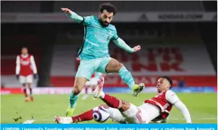  ?? — AFP ?? LONDON: Liverpool’s Egyptian midfielder Mohamed Salah (center) jumps over a challenge from Arsenal’s Brazilian defender Gabriel (right) during the English Premier League football match between Arsenal and Liverpool at the Emirates Stadium in London on April 3, 2021.