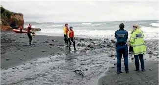 ?? PHOTO: FAIRFAX NZ ?? Police and lifesavers consult during the search for a youth missing off the coast of New Plymouth.