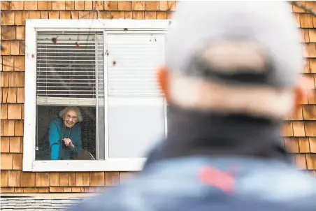  ?? Jessica Christian / The Chronicle ?? Marjorie Mann, 94, waves to son David from her secondfloo­r window at Waters Edge Lodge in Alameda in February.