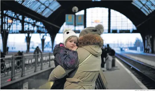  ?? BORJA SÁNCHEZ-TRILLO / EFE ?? Una madre y su hija esperan ayer en la estación Central de Lviv, desde la que abandonan Ucrania en tren a Polonia.