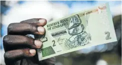  ?? Picture: Waldo Swiegers/Getty Images ?? A man holds a Zimbabwean two dollar bond banknote. The country recently introduced the real time gross settlement dollar.