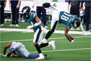 ?? AP Photo/Michael Ainsworth ?? ■ Philadelph­ia Eagles wide receiver Jalen Reagor (18) is upended by a Dallas Cowboys defender after catching a pass in the first half Sunday in Arlington, Texas.