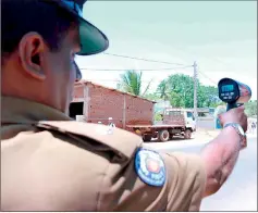  ??  ?? A police officer operating a speed gun to check the speed of an oncoming vehicle.