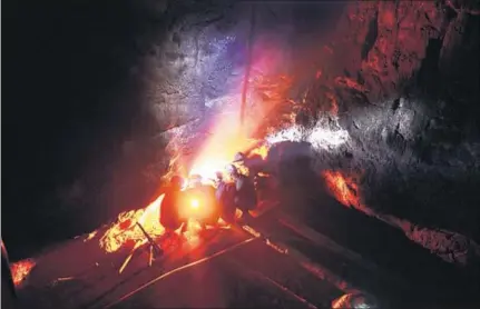  ?? AFP ?? ■ Miners keep warm by a fire inside a coal mine shaft near Rymbai village in Meghalaya.