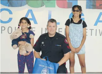  ?? FOR POSTMEDIA ?? Sgt. Paul Dunn went out of his way to replace the beloved teddy bear Ashlynn, left, lost at this year’s Stampede when out with her sister, Jasmine, and the rest of her family during BMO Kids’ Day.