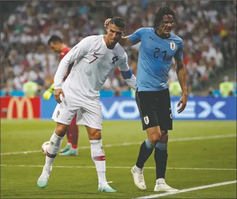  ?? The Associated Press ?? GOOD SPORT: Portugal’s Cristiano Ronaldo helps injured Uruguay’s Edinson Cavani walking out during the round of 16 match between Uruguay and Portugal at the 2018 World Cup at Fisht Stadium in Sochi, Russia, Saturday. Cavani scored both goals for...