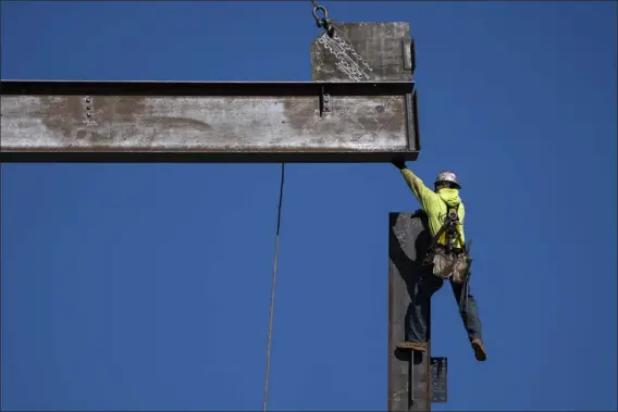  ?? MATT ROURKE — THE ASSOCIATED PRESS ?? An ironworker guides a beam during constructi­on of a municipal building in Norristown, Pa., on Feb. 15. The strength of the American job market has consistent­ly defied expectatio­ns throughout the economic tumult of the Covid-19years.