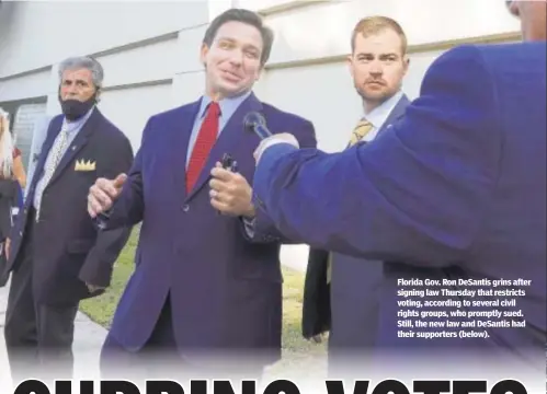  ??  ?? Florida Gov. Ron DeSantis grins after signing law Thursday that restricts voting, according to several civil rights groups, who promptly sued. Still, the new law and DeSantis had their supporters (below).