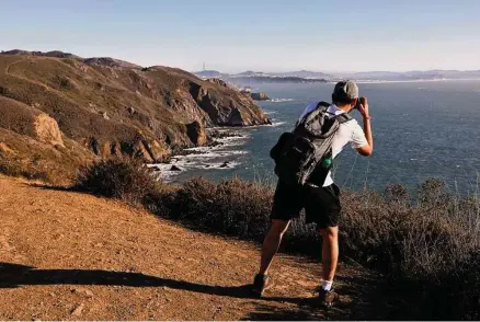  ?? Photos by Guy Wathen/The Chronicle ?? A hiker pauses to capture the view on Pirates Cove Trail in the Golden Gate National Recreation Area on an October day.