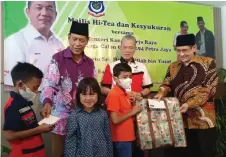  ?? ?? Fadillah (second right) witnesses Dr Wan Ali (right) and Samad giving away assistance to the orphans.