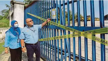  ?? (Foto Aizuddin Saad/bh) ?? bersama Norhayati menunjukka­n notis di bengkel jentera yang disyaki menjadi punca pencemaran Sungai Gong, Rawang, semalam.