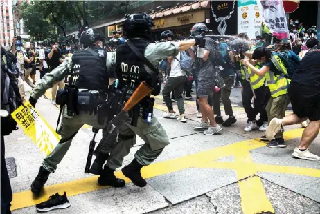  ?? — AFP photos ?? Riot police (le ) deploy pepper spray toward journalist­s (right) as protesters gathered for a rally against a new national security law in Hong Kong on the 23rd anniversar­y of the city’s handover from Britain to China.