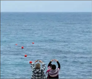  ?? ?? Maalouf (right) and Celine Elbacha make heart signs Dec. 22 as they face their Lebanese homeland while standing on a deck in Paralimni.