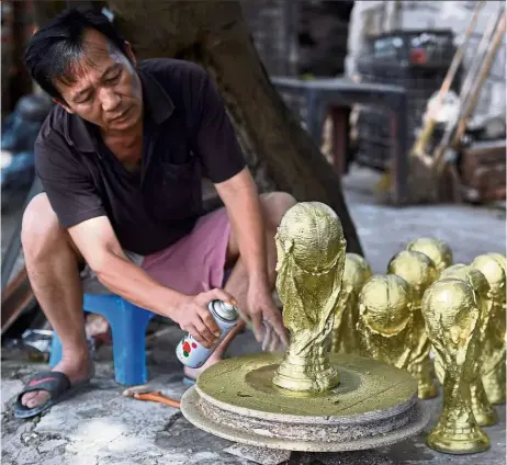  ?? — Photos: AFP ?? Vietnamese craftsman Vuong Hong Nhat has been making the foot-tall replicas since the 2010 World Cup in South Africa, perfecting his hand-carved design over several months to give as gifts.