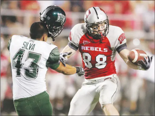  ?? SUN FILE (2009) ?? Hawaii defensive back Mana Silva loses his helmet after colliding with UNLV wide receiver Ryan Wolfe in a 2009 game at Sam Boyd Stadium. Wolfe, who would go on to be the Rebels all-time receptions leader, is among a group of 11 being inducted into the UNLV Athletics Hall of Fame today.