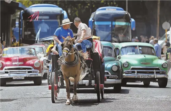  ?? MIAMI HERALD pHotos ?? ON A ROLL: Cuban street performer Yohan Ulloa portrays a famed Cuban tobacco roller in Vinales, right, which along with Havana, above, is a popular tourist destinatio­n in Cuba.