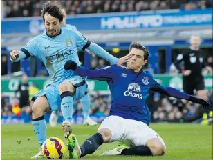  ?? — THE ASSOCIATED PRESS ?? Manchester City’s David Silva, left, fends off a tackle by Everton’s Muhamed Besic in English Premier League play on Saturday.