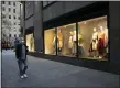  ?? AP PHOTO/MARK LENNIHAN ?? A man wearing a mask walks by a window display at a J.Crew store in Rockefelle­r Center, onSaturday in New York. The company announced Monday it would apply for bankruptcy protection amidst the COVID-19pandemic.