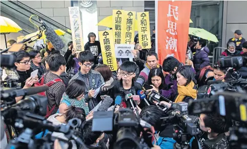  ?? EPA ?? Student activist Joshua Wong, centre, of the group Scholarism, talks to members of the media before reporting to Wan Chai Police Station in Hong Kong yesterday. Mr Wong is among more than 30 key figures of the civil disobedien­ce movement Occupy Central...