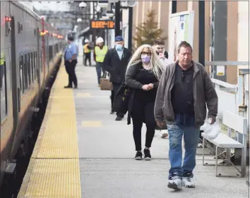  ?? Tyler Sizemore / Hearst Connecticu­t Media ?? Commuters disembark their train during the morning rush hour at the South Norwalk Train Station in Norwalk last week. Starting March 28, Metro-North will return to a nearly-full train schedule to complement the recent return of peak fares in an effort to get its service back to normal.