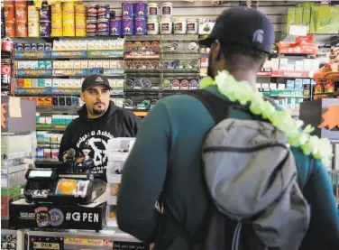  ?? Gabrielle Lurie / The Chronicle 2017 ?? Employee Majid Abbas ( left) helps a customer buy flavored tobacco at City Smoke and Vape Shop in San Francisco in 2017. Big Tobacco is seeking to reverse the state law barring sales of flavored products.