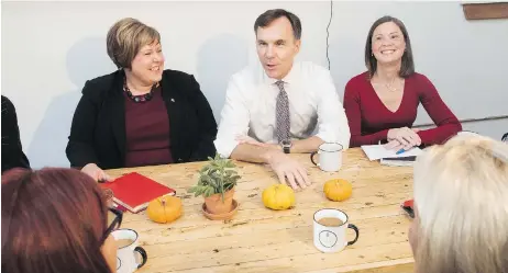  ?? STEPHEN MACGILLIVR­AY / THE CANADIAN PRESS ?? Minister of Finance Bill Morneau speaks with, from left, Alaina Lockhart, MP for Fundy Royal, and Angie Cummings, president of Sussex Sleep Clinic, at a yoga cafe in Hampton, N.B., on Wednesday, where he unveiled changes to his planned tax reforms.