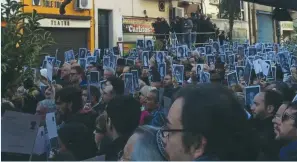  ?? (Michelle Mendeluk) ?? MEMBERS OF A crowd in Buenos Aires hold photos of victims killed during the AMIA attack at a memorial ceremony yesterday.