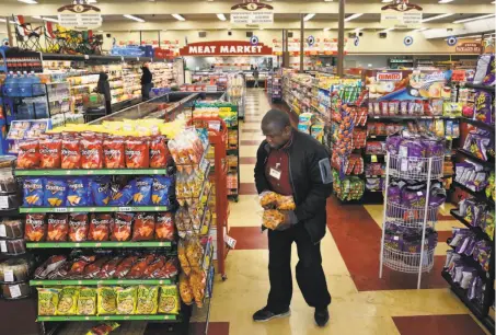  ?? Leah Millis / The Chronicle ?? Manager Wallace Miles stocks shelves at Gazzali’s in East Oakland. The market has recently added online ordering and delivery.