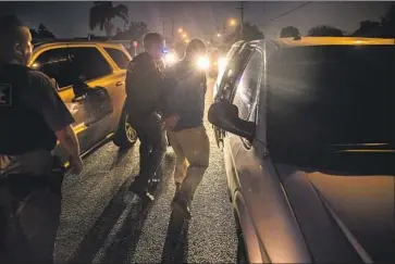  ?? Photograph­s by Brian van der Brug Los Angeles Times ?? FEDERAL IMMIGRATIO­N agents detain a Mexican national in Downey in 2017. President Trump this week renewed threats of nationwide ICE raids, raising anxiety among immigrants and skepticism among experts.