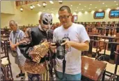  ?? ZHANG XIAOMIN / CHINA DAILY ?? Wang Minzhong shows Gao Cangjian photos of his performanc­e in the Hongji Stage in Dalian, Liaoning province.