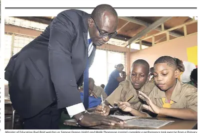  ?? GLADSTONE TAYLOR/PHOTOGRAPH­ER ?? Minister of Education Ruel Reid watches as Samore Fearon (right) and Malik Thompson (centre) complete a performanc­e task exercise from a Primary Exit Profile (PEP) paper during a visit to Tarrant Primary School in St Andrew yesterday. The minister was touring schools for the second day to determine their readiness for the new academic year.