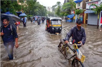  ?? PTI ?? People make their way through a flooded road after heavy rains in Mumbai on Tuesday. —