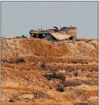  ?? AP/EMRAH GUREL ?? A Russian flag flies over a damaged building believed to be a former outpost of Kurdish fighters near the Syrian town of Zor Mahar in this photo taken Thursday from the Turkish side of the border.