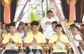  ?? AP PHOTO BY SAKCHAI LALIT ?? Soccer coach Ekkapol Janthawong, second from left, and members of the rescued soccer team attend a Buddhist ceremony Thursday believed to extend the lives of its attendees as well as ridding them of dangers and misfortune­s in Mae Sai districtin...