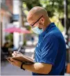  ??  ?? Matthew Krueger enters a note in a daily log that members of the COVID Resource Team are required to keep while patrolling in downtown Savannah.