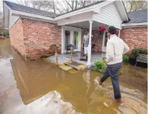  ?? MICKEY WELSH/THE MONTGOMERY ADVERTISER/AP ?? After torrential rain flooded roads in Alabama, Gregory Shuford, left, and Terease Shuford keep an eye on water levels in west Montgomery, Ala., on Christmas morning.