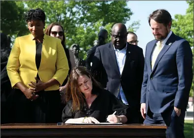  ?? (Arkansas Democrat-Gazette/Stephen Swofford) ?? Arkansas Rep. Denise Ennett (from left) and Sens. Fred Allen and Clarke Tucker, all Democrats from Little Rock, stand behind Gov. Sarah Huckabee Sanders in front of the Little Rock Nine monument on the north side of the state Capitol in Little Rock on Tuesday as she signs a bill to allow a specialty license plate in honor of Central High School.