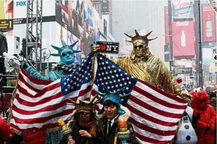  ??  ?? The show must go on: People dressed up as the Statue of Liberty posing for pictures at Times Square during a snowfall in Manhattan, New York. — Reuters