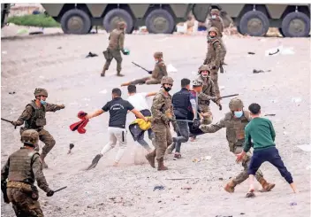  ?? FOTO: BERNAT ARMANGUE/DPA ?? Spanische Soldaten versuchen, Migranten, die vor wenigen Minuten am Strand von Ceuta eingetroff­en sind, festzunehm­en und nach Marokko abzuschieb­en.