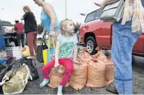  ??  ?? Sophia Johnson, 6, and her mother, Kace Johnson, take a break after filling sandbags with dirt in Sarasota in preparatio­n for Hurricane Irma.