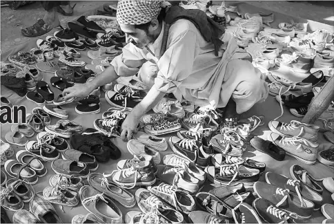  ?? — WP-Bloomberg photos ?? A vendor arranges a display of shoes in a market in Karachi, Pakistan, on May 31, 2015.